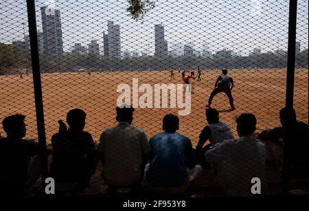 Silhouette von Teenagern, die hinter einem Zaun stehen und ein Cricket-Spiel im Shivaji Park in Mumbai-Dadar, Maharashtra, Indien, beobachten Stockfoto