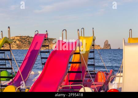 Bunte Tretboote oder Paddelboote mit Rodel am Strand.Sommerkonzept mit Tretbooten mit dem Mittelmeer im Hintergrund.Spanien. Stockfoto