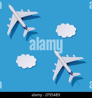 Miniatur Spielzeug Flugzeug auf bunten Papier Hintergrund. Flaches Lay-Design des Reisekonzepts mit Flugzeug und Wolken am blauen Himmel. Nahtlose Textur. Stockfoto