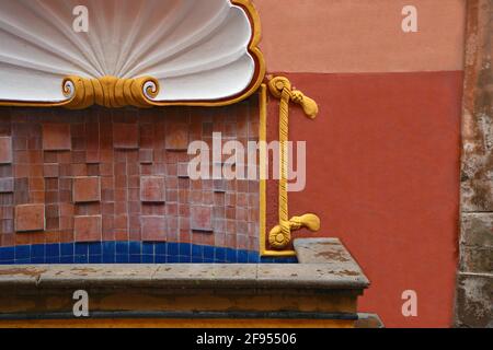 Schalenförmige, geflieste Wasserfontäne an einer venezianischen Stuckwand in Santiago de Querétaro, Mexiko. Stockfoto