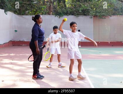 Kleine Kinder, die Tennisunterricht mit einem Trainer an der SPG (Shivaji Park Gymkhana) Tennis Academy in Mumbai, Maharashtra, Indien, haben. Stockfoto