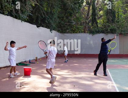 Kleine Kinder, die Tennisunterricht mit einem Trainer an der SPG (Shivaji Park Gymkhana) Tennis Academy in Mumbai, Maharashtra, Indien, haben. Stockfoto