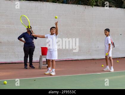 Kleine Kinder, die Tennisunterricht mit einem Trainer an der SPG (Shivaji Park Gymkhana) Tennis Academy in Mumbai, Maharashtra, Indien, haben. Stockfoto