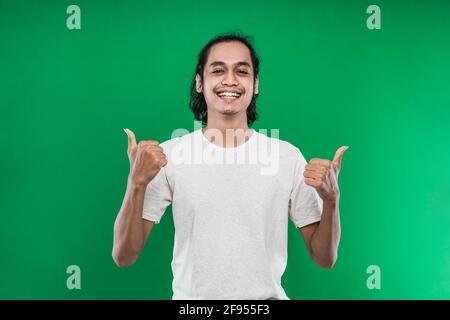 Ein hübscher Mann, der zwei Hände hebt und gleichzeitig den Daumen zeigt Kamera mit Lächeln Stockfoto
