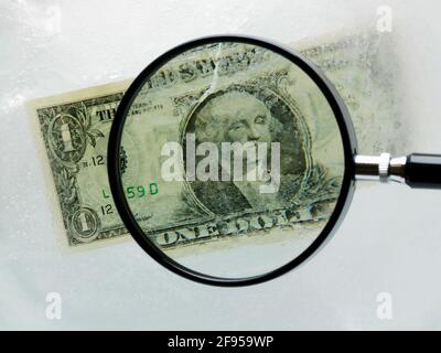 Der amerikanische Dollar-Schein ist in Eis gehüllt und wird durch eine Lupe betrachtet Glas Stockfoto