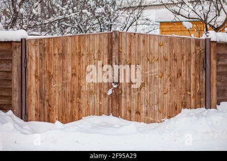 Verschneite Gartentore verschneite Holztore nach einem Schneesturm. Winterhintergrund. Stockfoto