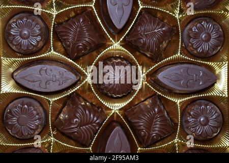 Schokoladen-Bonbons in verschiedenen Formen in einer Goldschachtel, Draufsicht. Verschiedene Schokoladenpralinen. Stockfoto