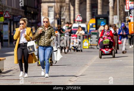 Dundee, Tayside, Schottland, Großbritannien. April 2021. UK Wetter: Ein sonniger, kühler Tag in Nordostschottland mit Temperaturen von bis zu 14 Grad Covid-19 Lockdown wird mit den Menschen, die im Stadtzentrum von Dundee einkaufen und Kontakte knüpfen, gelockert, da einige wichtige Einzelhandelsgeschäfte in der Hauptstraße eröffnet werden. Zwei modische Frauen nutzen die neuen lockeren Sperrbestimmungen und das sonnige Aprilwetter, um während eines Tages beim Einkaufen zusammen Kaffee zu trinken. Kredit: Dundee Photographics/Alamy Live Nachrichten Stockfoto