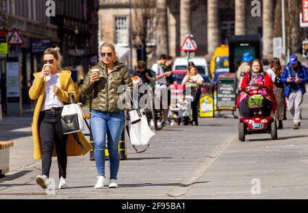 Dundee, Tayside, Schottland, Großbritannien. April 2021. UK Wetter: Ein sonniger, kühler Tag in Nordostschottland mit Temperaturen von bis zu 14 Grad Covid-19 Lockdown wird mit den Menschen, die im Stadtzentrum von Dundee einkaufen und Kontakte knüpfen, gelockert, da einige wichtige Einzelhandelsgeschäfte in der Hauptstraße eröffnet werden. Zwei modische Frauen nutzen die neuen lockeren Sperrbestimmungen und das sonnige Aprilwetter, um während eines Tages beim Einkaufen zusammen Kaffee zu trinken. Kredit: Dundee Photographics/Alamy Live Nachrichten Stockfoto