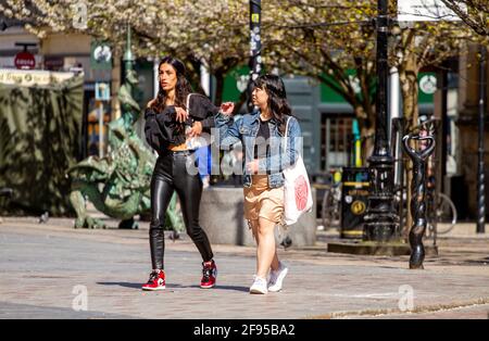 Dundee, Tayside, Schottland, Großbritannien. April 2021. UK Wetter: Ein sonniger, kühler Tag in Nordostschottland mit Temperaturen von bis zu 14 Grad Covid-19 Lockdown wird mit den Menschen, die im Stadtzentrum von Dundee einkaufen und Kontakte knüpfen, gelockert, da einige wichtige Einzelhandelsgeschäfte in der Hauptstraße eröffnet werden. Zwei modische Frauen nutzen die neuen lockeren Sperrbestimmungen und das sonnige Aprilwetter, das beim Einkaufen zusammen läuft. Kredit: Dundee Photographics/Alamy Live Nachrichten Stockfoto