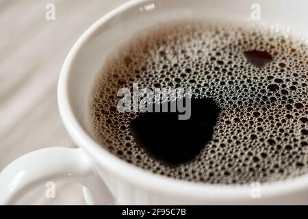 Tasse schwarzen Kaffee in einer weißen Tasse auf einer hölzernen Oberfläche, von oben gesehen Stockfoto