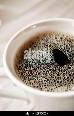 Tasse schwarzen Kaffee in einer weißen Tasse auf einer hölzernen Oberfläche, von oben gesehen Stockfoto