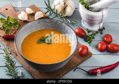 Köstliche, farbige Linsensuppe mit Herbes, Tomaten, Chili und Knoblauch auf einem grauen Tisch Stockfoto