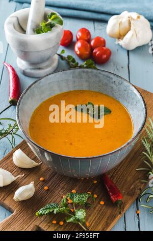 Köstliche, farbige Linsensuppe mit Herbes, Tomaten, Chili und Knoblauch auf einem grauen Tisch Stockfoto