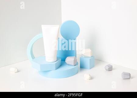 Eine leere Kosmetikröhre und hellblaue geometrische Formen bilden ein Podium, eine Plattform auf weißem Hintergrund Stockfoto