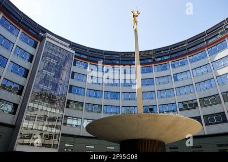 London, Großbritannien - 4. April 2021: Die vergoldete Bronzefigur von Helios, dem allsehenden Sonnengott der griechischen Mythologie, der den zentralen Innenhof des Fernsehzentrums in White City schmückt. Die Statue, die vom Bildhauer T B Huxley-Jones entworfen wurde, wurde für den ehemaligen BBC-Sender, der 1960 eröffnet wurde, in Auftrag gegeben. Die Statue stellt die Ausstrahlung des Fernsehlichts auf der ganzen Welt dar und sitzt in der Mitte eines Brunnens und zwei liegende Figuren, die Ton und Vision repräsentieren, die beiden Komponenten des Fernsehens. Stockfoto