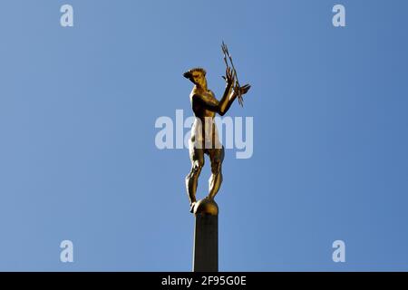 London, Großbritannien - 4. April 2021: Die vergoldete Bronzefigur von Helios, dem allsehenden Sonnengott der griechischen Mythologie, der den zentralen Innenhof des Fernsehzentrums in White City schmückt. Die Statue, die vom Bildhauer T B Huxley-Jones entworfen wurde, wurde für den ehemaligen BBC-Sender, der 1960 eröffnet wurde, in Auftrag gegeben. Die Statue stellt die Ausstrahlung des Fernsehlichts auf der ganzen Welt dar und sitzt in der Mitte eines Brunnens und zwei liegende Figuren, die Ton und Vision repräsentieren, die beiden Komponenten des Fernsehens. Stockfoto