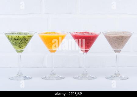 Smoothies in martini-Gläsern aus Kiwi, sizilianischem Orange, Mandarine und Banane Stockfoto