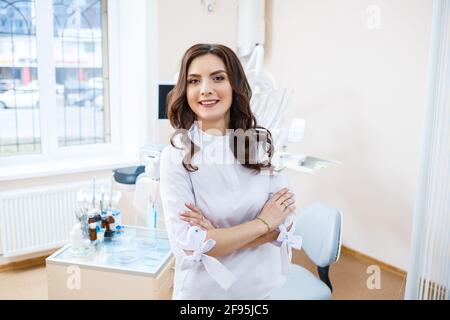 Zahnarzt am Arbeitsplatz. Ein fröhlicher Arzt sitzt in einem geräumigen, modernen Büro mit einem freundlichen Lächeln Stockfoto