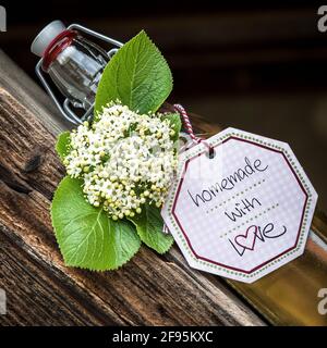 Glasflasche mit hausgemachtem Holunderblütensirup auf einem alten Holzstuhl. Stockfoto