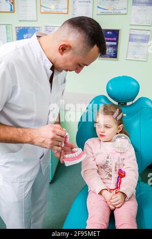 Professioneller Arzt, pädiatrischer Zahnarzt lehrt ein Kind, seine Zähne zu putzen. Zahnarztpraxis für Patientenuntersuchung. Der Prozess der zahnärztlichen Behandlung in einem Stockfoto