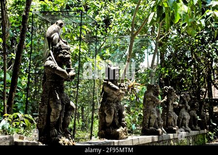 Affe sitzt auf einer balinesischen Hindu-Statue im Affenwald. Mandala Suci Wenara Wana, oder auch bekannt als Ubud Monkey Forest, Heiligtum. Stockfoto