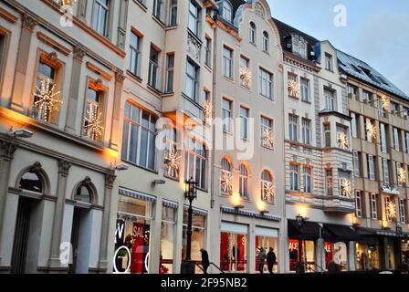 Bonn, Deutschland: Eine Reihe weißer europäischer Ladenfronten an der Martinsplatz-Straße, die für Weihnachtsverkäufe mit Urlaubskäufern geschmückt sind. Stockfoto