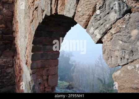 LANDSTUHL, DEUTSCHLAND: Burg Nanstein (Burg Nanstein) in Landstuhl, Deutschland an einem nebligen, nebligen Morgen. Ein Steinbogen mit Blick auf den umliegenden Wald. Stockfoto