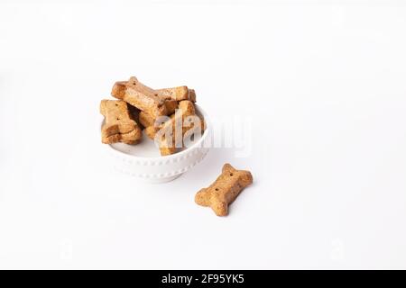 Haufen von braunen Knochen geformten Hund Leckereien auf Kuchen Sockel Auf weißem Hintergrund Stockfoto