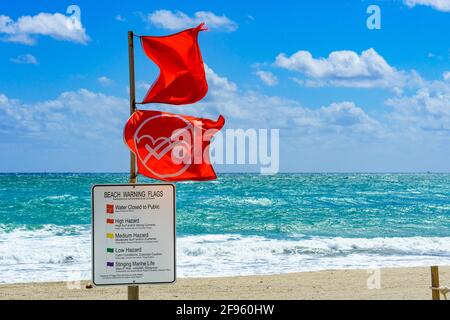 Das Wasser ist für öffentliche rote Warnflaggen und Informationszeichen vor dem rauhen, rauhen Ozean - Hollywood, Florida, USA, geschlossen Stockfoto