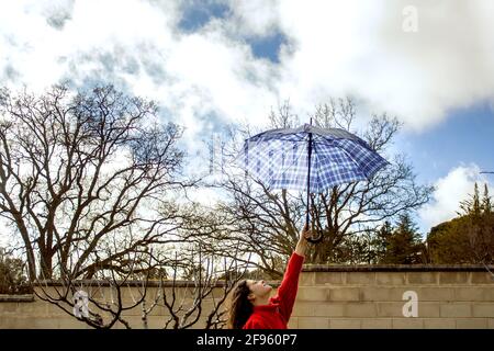 Der Arm der Frau hält einen Regenschirm gegen den bewölkten Himmel Stockfoto