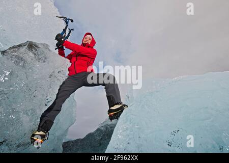 Frau klettert Eisberg an der Südküste Islands mit Eispicker Stockfoto