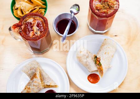 Mexikanisches Burrito- und Michelada-Bier mit Tomatensaft und Kopierraum. Stockfoto