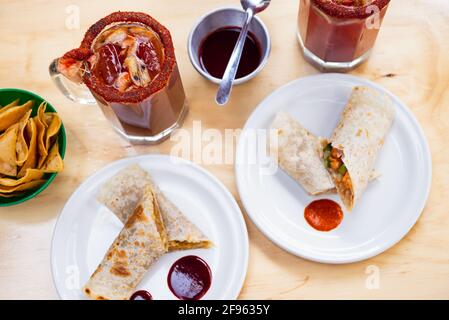 Mexikanisches Burrito- und Michelada-Bier mit Tomatensaft und Kopierraum. Stockfoto