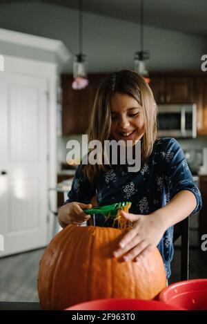 Mädchen schaufelt an halloween Kürbiskerne aus einem Kürbis Stockfoto