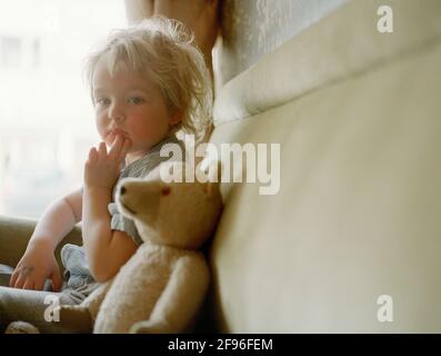 Boy sitzt auf dem Sofa mit Teddybär Stockfoto