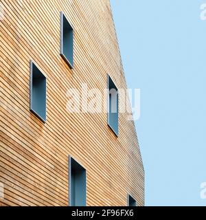 Holzwand eines modernen Gebäudes mit Fenstern zum blauen Himmel Stockfoto