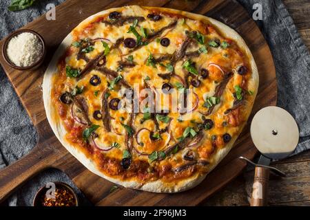 Hausgemachte Gourmet-Sardellenpizza mit Oliven und Basilikum Stockfoto