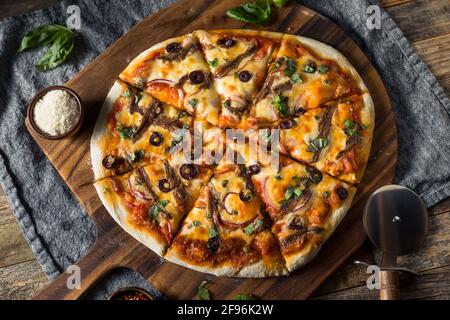 Hausgemachte Gourmet-Sardellenpizza mit Oliven und Basilikum Stockfoto