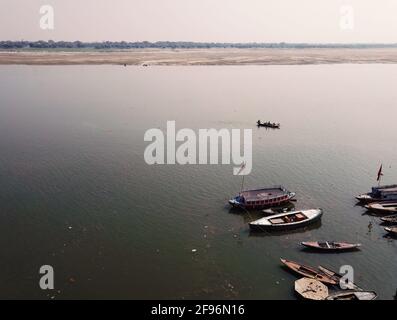 Luftaufnahme von oben auf bunte Holzboote angedockt auf einem ghat von varanasi auf dem Ganges oder ganga Fluss während Nebel Umwelt Stockfoto