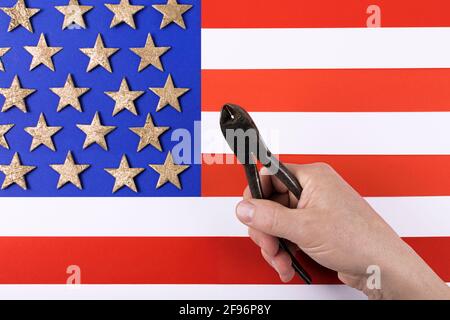 Alte Metallzange in der Hand des Mannes über der amerikanischen Flagge. Happy Labor Day Konzept. Internationale Feier. Speicherplatz kopieren. Flach liegend. Stockfoto
