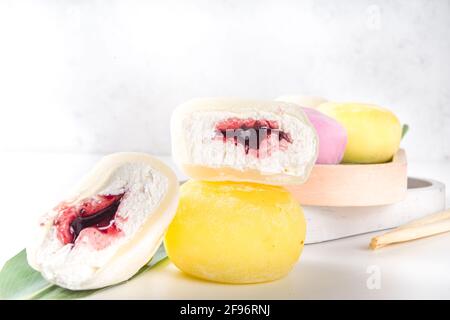 Traditionelles japanisches Dessert-Mochi. Buntes Mochi-Eis auf einem weißen Tisch, ganz und mit Beerenfrüchten, Fruchtfüllung geschnitten Stockfoto
