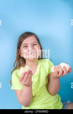 Niedliche Vorschulkinder genießen japanische süße Mochi. Mädchen Kind essen trendige Mochi Eis mit Fruchtaromen, auf einem hellblauen Hintergrund Stockfoto
