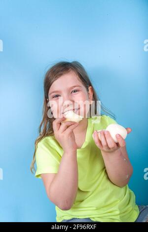 Niedliche Vorschulkinder genießen japanische süße Mochi. Mädchen Kind essen trendige Mochi Eis mit Fruchtaromen, auf einem hellblauen Hintergrund Stockfoto