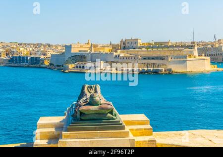 Das Denkmal erinnert an den zweiten Weltkrieg in Form eines bronzenen Soldaten, der auf einer Katafalke mit Blick auf den Grand Harbour und das Fort St. Angelo, Valletta, Stockfoto