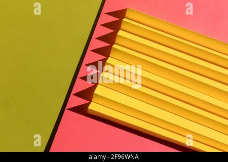 Abstrakte Papiertextur in Grün, Gelb und Rosa. Gefaltetes Papier mit harten Sonnenschattierungen, geometrischen Formen und Linien. Minimalistischer Hintergrund. Flat la Stockfoto