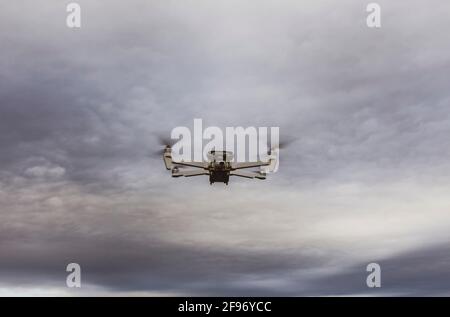 Weiße FIMI-Drohne in der Luft, die bei Sonnenuntergang gegen den bewölkten Himmel fliegt Stockfoto