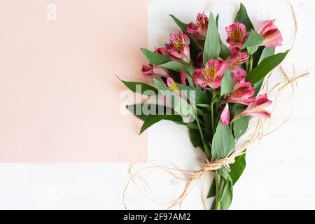 Bouquet von frischen Alstroemeria Blumen auf weißem Holz Hintergrund mit Pinkfarbener Papierkopierplatz Stockfoto