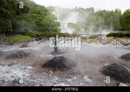 Ein Mann, der ein Loch in Fumarolis da Lagoa das Furnas für Cozido das Furnas auf der Insel Sao Miguel auf den Azoren, Portugal, grub Stockfoto