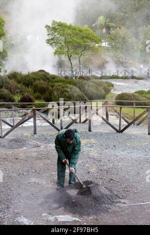 Ein Mann, der ein Loch in Fumarolis da Lagoa das Furnas für Cozido das Furnas auf der Insel Sao Miguel auf den Azoren, Portugal, grub Stockfoto